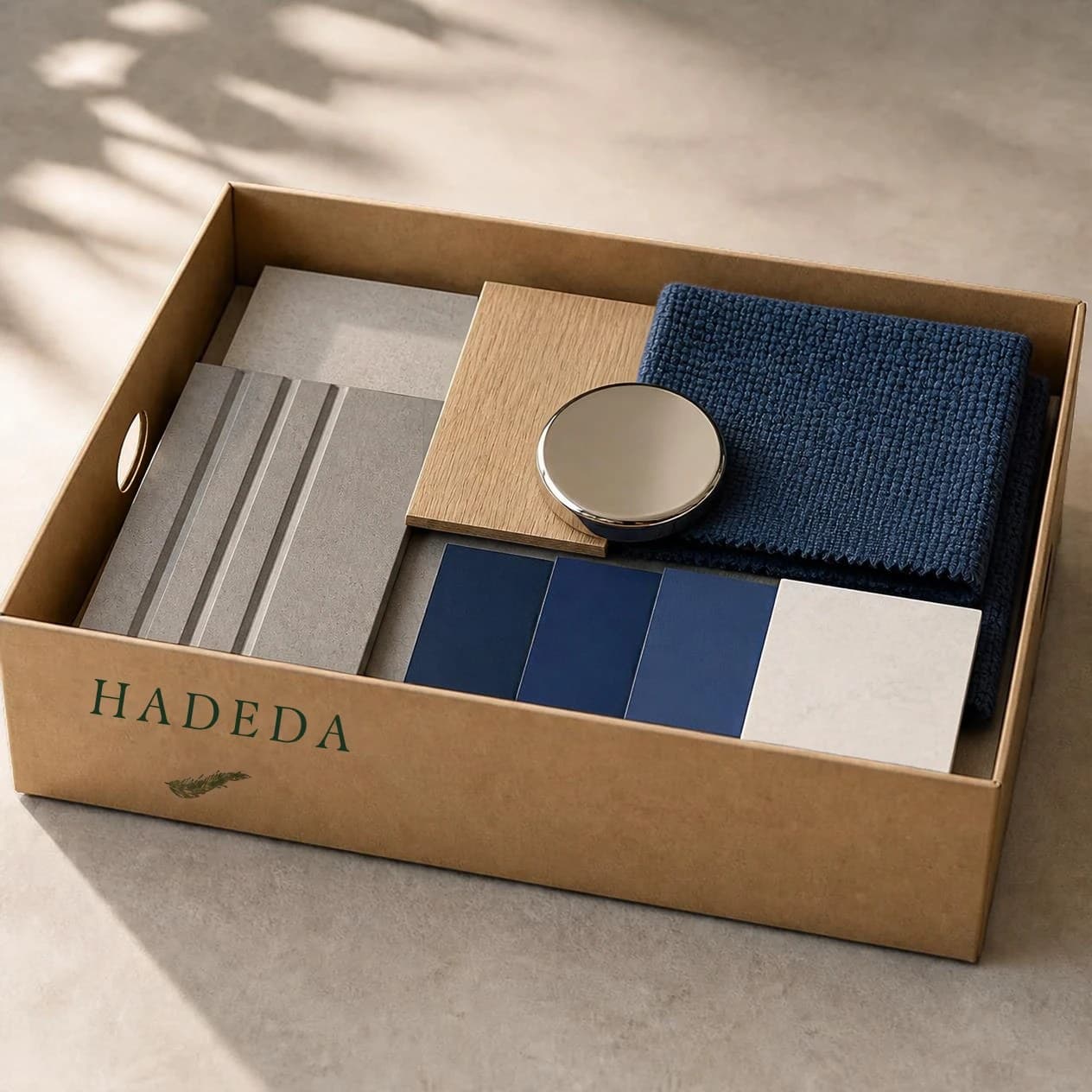 Hadeda Studio sample box: navy tile, oak, brushed nickel and a deep blue bouclé in a branded box